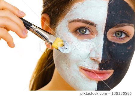 Girl black mask on half face apply white mud Girl black mask on half face apply white mud 138330595