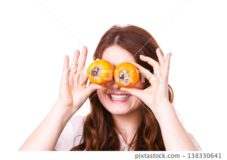 Woman holds persimmon kaki fruits on eyes, isolated Woman holds persimmon kaki fruits on eyes, isolated 138330641