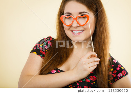 Happy woman holding fake eyeglasses on stick Happy woman holding fake eyeglasses on stick 138330650