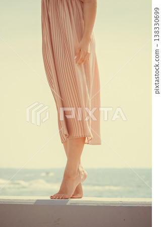 Woman wearing long light pink dress on jetty 138330699