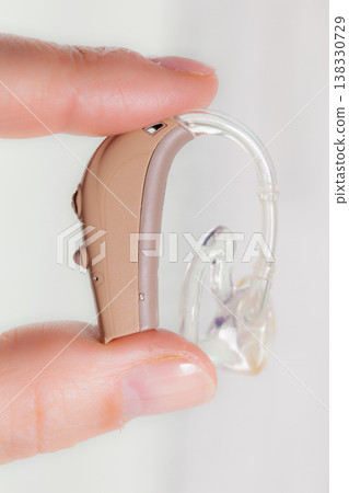senior person holding hearing aid closeup senior person holding hearing aid closeup 138330729