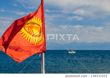 National flag of Kyrgyzstan and boat on calm waters of Issyk-Kul lake National flag of Kyrgyzstan and boat on calm waters of Issyk-Kul lake 138331035