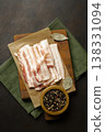 Raw bacon on wooden cutting board on brown background. 138331094