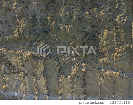 Weathered Cheap Uneven Concrete Surface with Pebbles under tangential harsh light 138331110