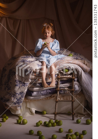 Little girl in blue dress with crown sitting on mattresses with apples, princess and the pea Little girl in blue dress with crown sitting on mattresses with apples, princess and the pea 138331743