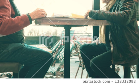 Two unrecognizable senior men talking while seated at a cafe table near a window 138332098
