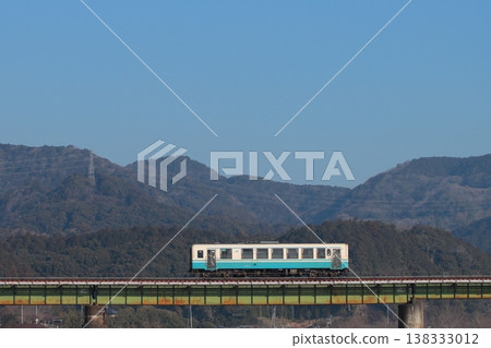 A KiHa 32 series diesel railcar crosses a railway bridge with the majestic Shikoku Mountains in the background. (Photographed on February 21, 2026) A KiHa 32 series diesel railcar crosses a railway bridge with the majestic Shikoku Mountains in the background. (Photographed on February 21, 2026) 138333012
