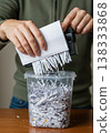 Person Shredding Documents Into a Plastic Container Revealing Confidential Information 138333868