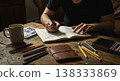 Person Sketching In Notebook With Colored Pencils And A Cup Of Coffee On A Wooden Table Interior 138333869