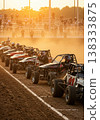 Race Cars Lined Up On The Dirt Track Ready For The Start Golden Hour Sunlight And Crowd In The Background 138333875