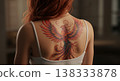 Rear View Of A Woman With A Phoenix Tattoo On Her Back With Red Hair and Soft Lighting 138333878
