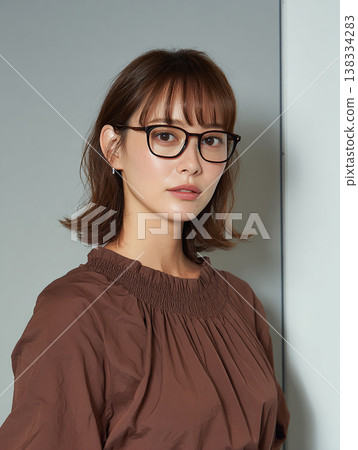 一位身穿棕色襯衫、戴著眼鏡的女士，舉止沉穩睿智。 138334283