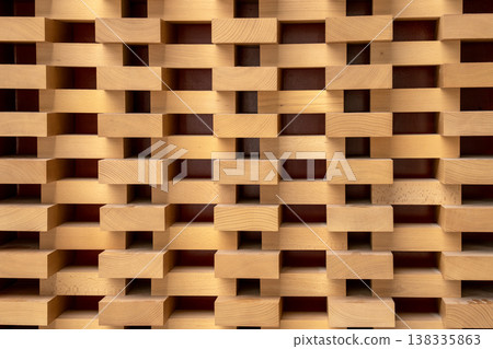 Abstract architectural wood wall with a repetitive geometric pattern of blocks. Minimalist timber texture with rhythmic highlights and shadows for modern interior design and background use. 138335863