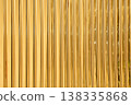 Glossy gold foil fringe curtain backdrop featuring vertical metallic lines. These shimmering golden tinsel strips create a festive texture for celebrations, parties, and glamorous holiday events. 138335868
