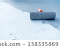 Close-up of a paint roller applying white liquid coating or sealant on a grey industrial floor. Construction site floor renovation and waterproofing process. Space for text on the surface. 138335869