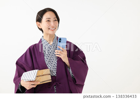身穿浴衣的女子手持智慧型手機 身穿浴衣的女子手持智慧型手機 138336433