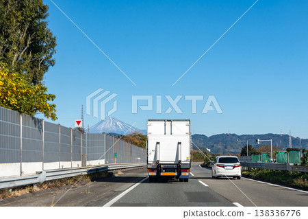 一輛卡車和一輛轎車行駛在靜岡縣靜岡市東名高速公路清水交流道附近，可以看到富士山。 138336776