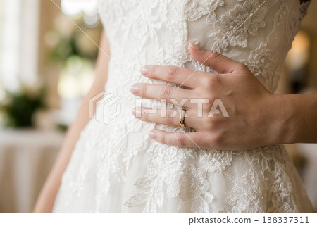 新娘的手戴著一枚金色的結婚戒指，輕輕撫摸她的蕾絲婚紗。 138337311
