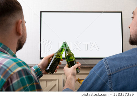 Two friends raise beer bottles while enjoying a football game Two friends raise beer bottles while enjoying a football game 138337359