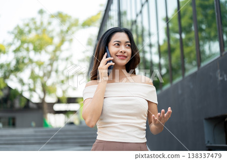 Pretty asian woman open one palm talking on phone call while standing walking on stairs by building. Pretty asian woman open one palm talking on phone call while standing walking on stairs by building. 138337479