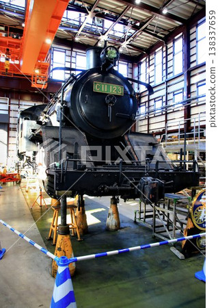 The boiler and chassis of the steam locomotive 'C11-123' undergoing disassembly and maintenance in the maintenance shed. 138337659