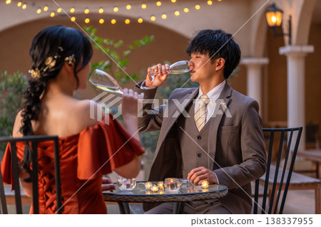 一對新人穿著晚宴婚禮禮服，在晚餐時喝香檳。 138337955