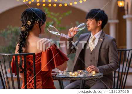 一對新人穿著晚宴婚禮禮服,在晚餐時喝香檳。 一對新人穿著晚宴婚禮禮服,在晚餐時喝香檳。 138337956
