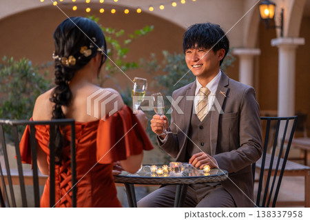一對新人穿著晚宴婚禮禮服，在晚餐時喝香檳。 138337958