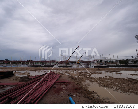 Construction site muddy ground steel pipe crane cloudy sky frame construction with crane muddy Construction site muddy ground steel pipe crane cloudy sky frame construction with crane muddy 138338108