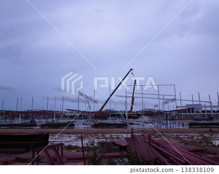 Construction site steel structure crane framework industrial muddy ground evening sky development 138338109