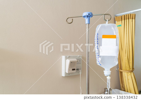 Medical IV drip bag hanging on stand in hospital room with fluid therapy equipment healthcare treatment hydration and patient care environment Medical IV drip bag hanging on stand in hospital room with fluid therapy equipment healthcare treatment hydration and patient care environment 138338432
