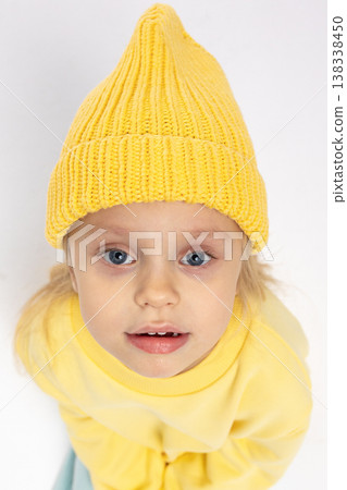 Portrait of beautiful cute little toddler girl. Child with funny face in yellow sweatshirt and yellow hat. Pretty smile kid in studio on white background. High quality photo Portrait of beautiful cute little toddler girl. Child with funny face in yellow sweatshirt and yellow hat. Pretty smile kid in studio on white background. High quality photo 138338450