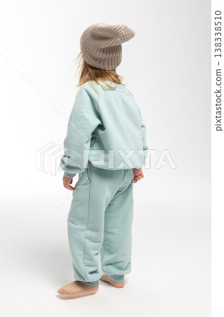 Portrait of beautiful cute little toddler girl. Child with funny face in mint sweatshirt and hat. Pretty smile kid in studio on white background. Portrait of beautiful cute little toddler girl. Child with funny face in mint sweatshirt and hat. Pretty smile kid in studio on white background. 138338510