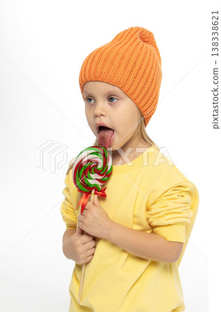 Portrait of funny little blonde girl with sweets lollipop in her hand. High quality photo 138338621