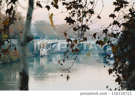Classical architecture and arched bridge over river with soft evening tones and reflections creating timeless urban landscape in Italy, Rome, Italy. Classical architecture and arched bridge over river with soft evening tones and reflections creating timeless urban landscape in Italy, Rome, Italy. 138338721