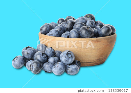 Blueberries sit in a wooden bowl with some outside 138339017