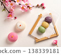 精選幾款應景的日式春日甜點，包括櫻花麻糬和三色團子。俯視圖，紙上印有櫻花圖案。 138339181