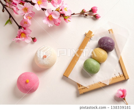 精選幾款應景的日式春日甜點，包括櫻花麻糬和三色團子。俯視圖，紙上印有櫻花圖案。 138339181