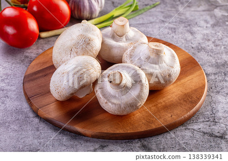 Fresh white champignon mushrooms on a wooden board with raw vegetables. Fresh white champignon mushrooms on a wooden board with raw vegetables. 138339341