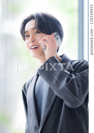 一位年輕的男性商務人士接聽電話,提供可靠的客戶服務,包括銷售、溝通和諮詢。 一位年輕的男性商務人士接聽電話,提供可靠的客戶服務,包括銷售、溝通和諮詢。 138339453