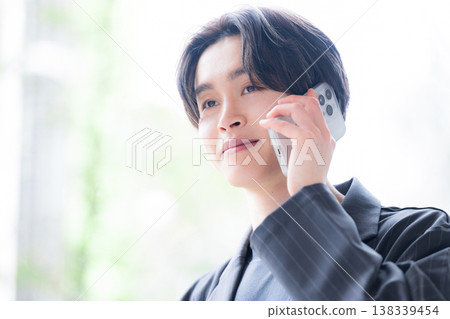 一位年輕的男性商務人士接聽電話,提供可靠的客戶服務,包括銷售、溝通和諮詢。 一位年輕的男性商務人士接聽電話,提供可靠的客戶服務,包括銷售、溝通和諮詢。 138339454