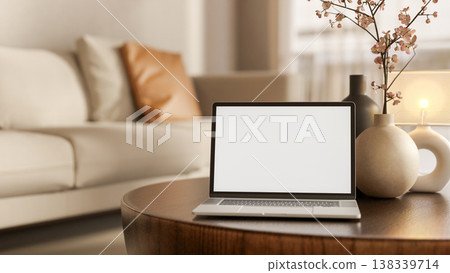 White screen laptop with flower vase and lamp on round wooden table aside sofa in modern living room 138339714