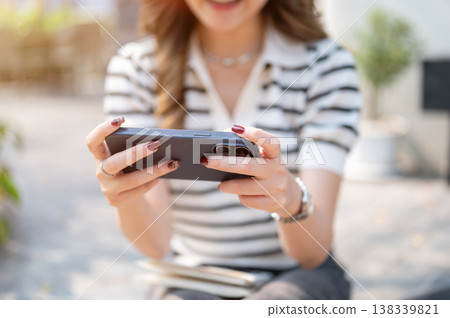 Close up of woman with polished nails holding looking at horizontal phone sitting on pavement ground Close up of woman with polished nails holding looking at horizontal phone sitting on pavement ground 138339821