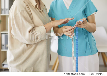 Senior woman waist measurement by nurse during clinic checkup and consultation 138339956