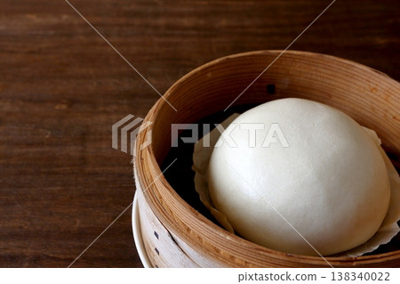 Chinese steamed buns in a bamboo steamer, shown in the background of the table. Chinese steamed buns in a bamboo steamer, shown in the background of the table. 138340022