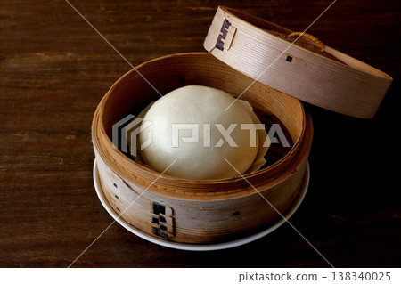 Chinese steamed buns in a bamboo steamer, shown in the background of the table. 138340025