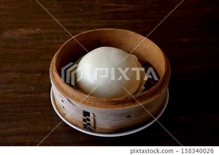 Chinese steamed buns in a bamboo steamer, shown in the background of the table. Chinese steamed buns in a bamboo steamer, shown in the background of the table. 138340026