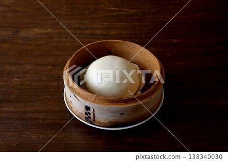 Chinese steamed buns in a bamboo steamer, shown in the background of the table. Chinese steamed buns in a bamboo steamer, shown in the background of the table. 138340030