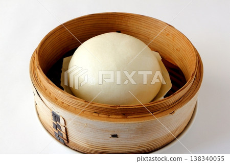Chinese steamed buns in a steamer basket against a white background Chinese steamed buns in a steamer basket against a white background 138340055