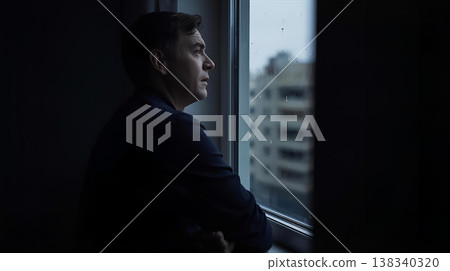 一名男子正望著窗外查看天氣。 138340320